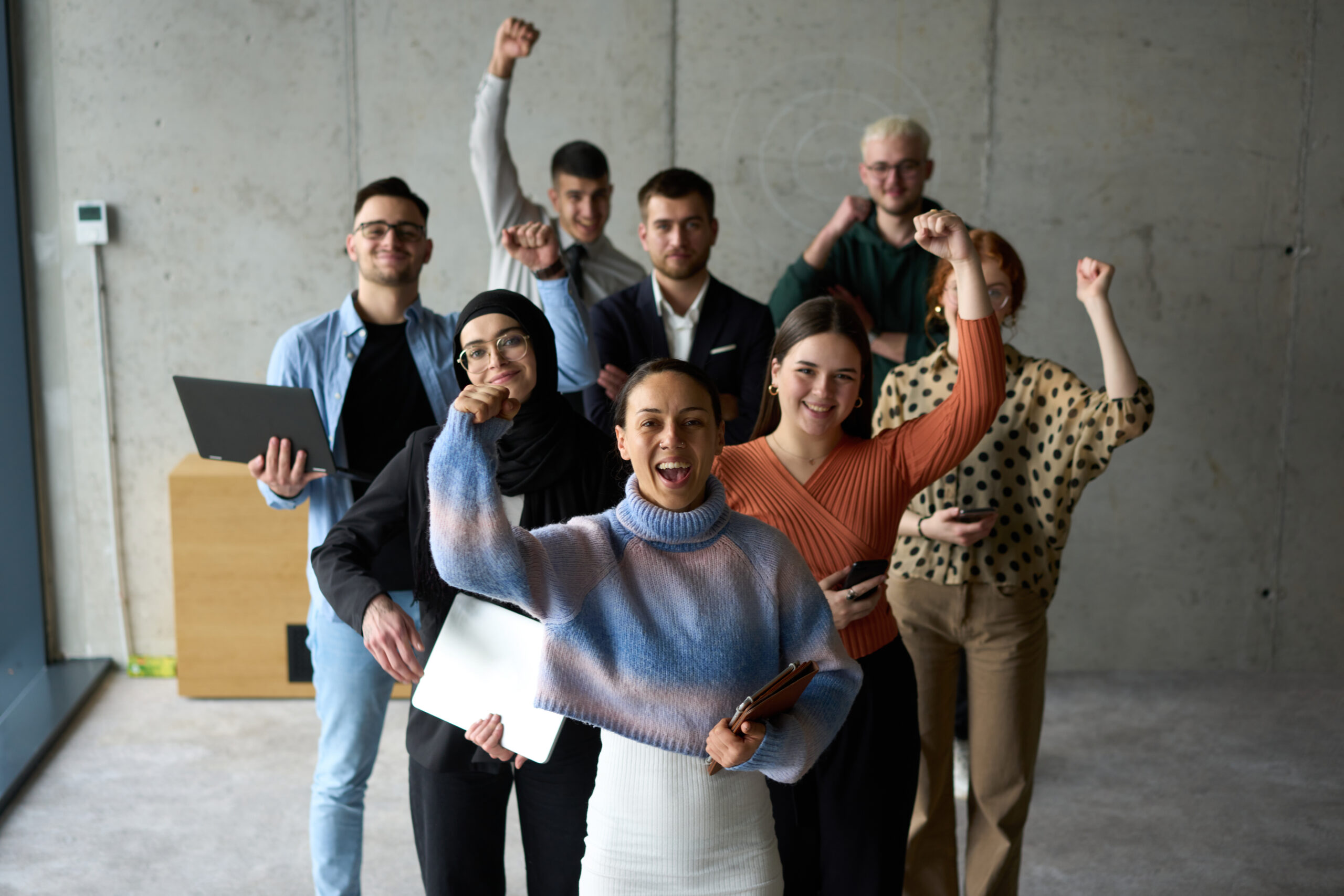 A diverse team of business professionals ecstatically celebrating their success in a modern office, expressing triumph and unity after achieving their goals