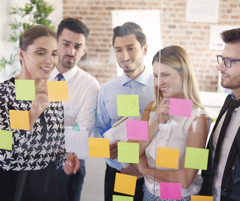 Team behind glass with colorful papers