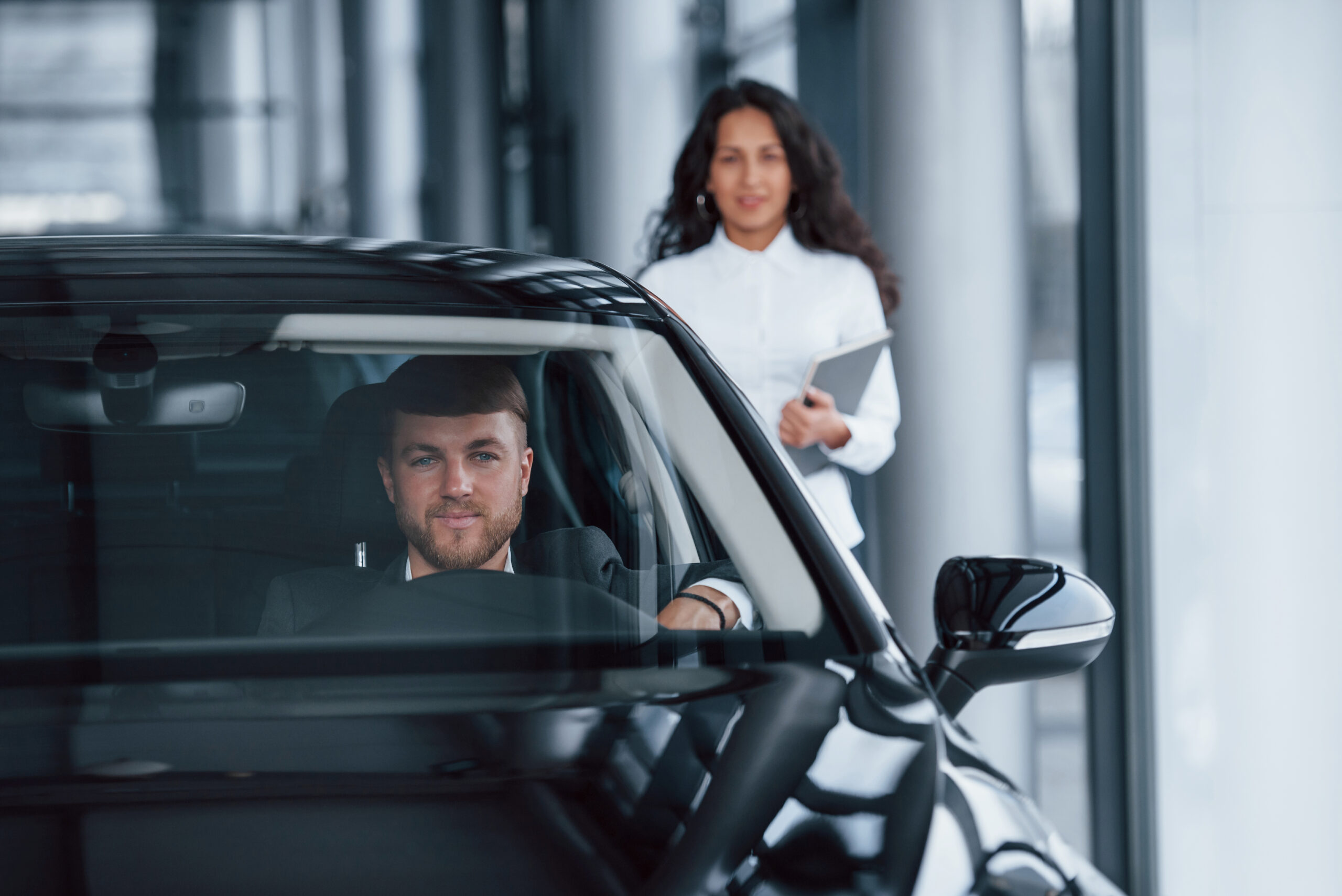 Just owned. Male customer and modern businesswoman in the automobile saloon